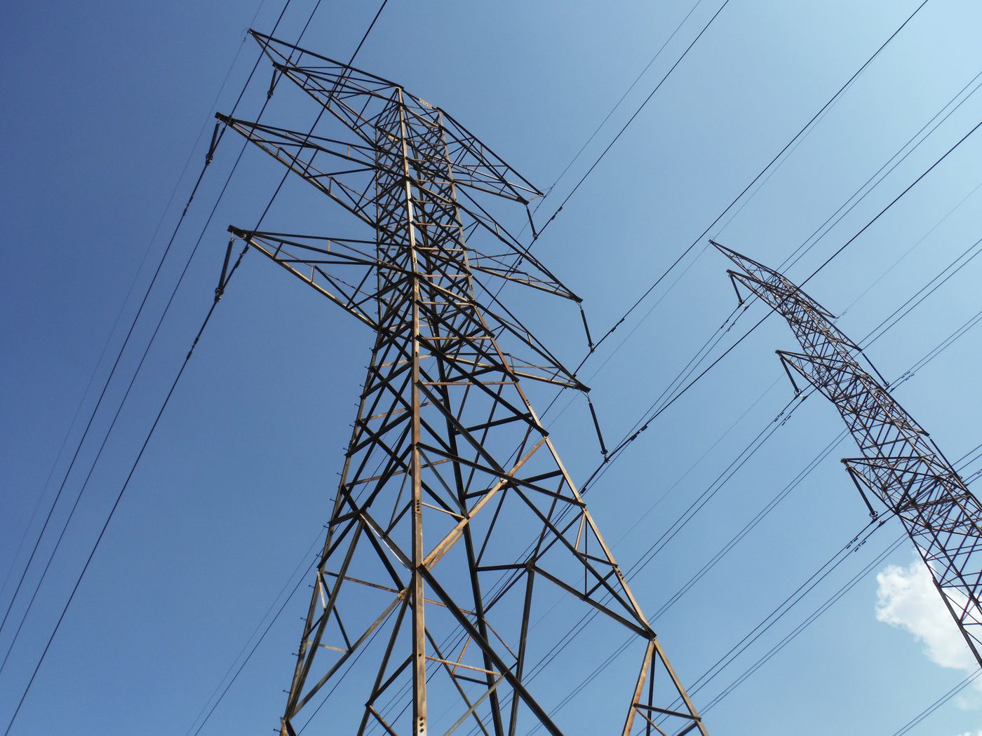 Hochspannungsmasten und Stromleitungen vor blauem Himmel